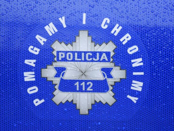 Drzwi policyjnego radiowozu z policyjną gwiazdą i napisem pomagamy i chronimy oraz policja 112