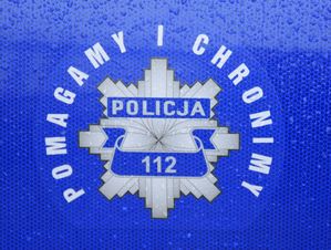 Policyjna gwiazda na drzwiach radiowozu. Napis POMAGAMY I CHRONIMY oraz POLICJA 112