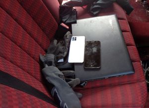 Laptop i dwa telefony które leżą na siedzeniu w pojeździe