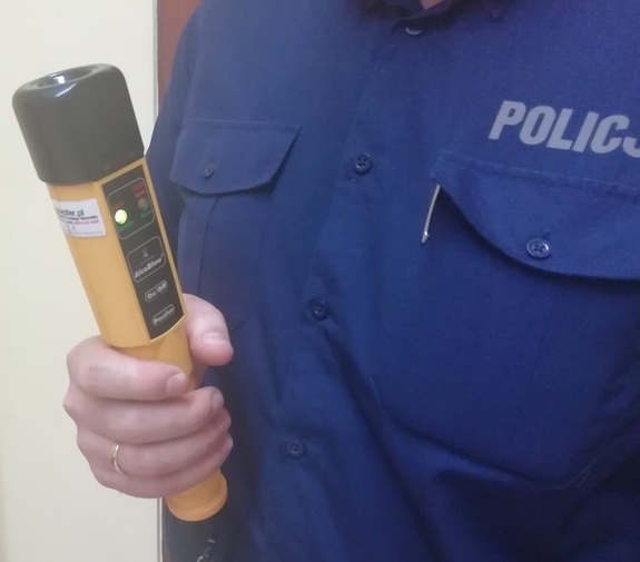 policjant trzymający urządzenie do badania stanu trzeźwości
