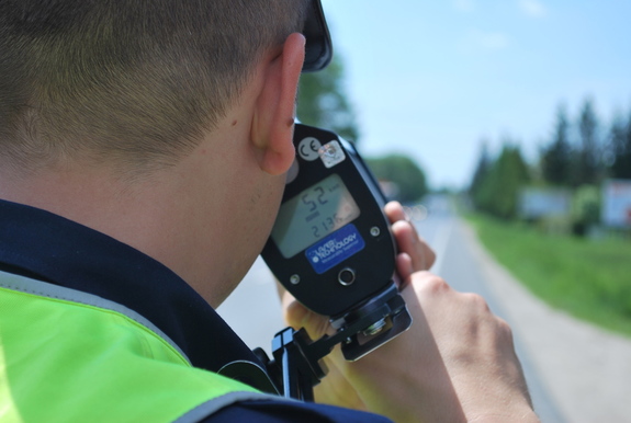 Na zdjęciu policjant ruchu drogowego dokonuje pomiaru i laserowym miernikiem prędkości.