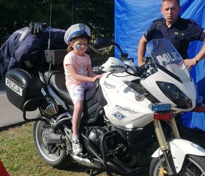 Dziecko na policyjnym motocyklu. Obok stoi policjant