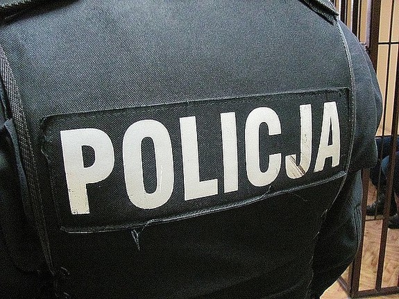 Plecy policjanta - na czarnej kamizelce biały napis POLICJA