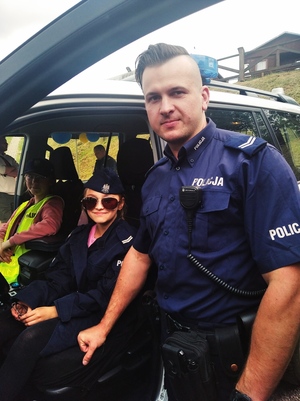 Dzieci w policyjnym radiowozie w przebraniu policjantów.