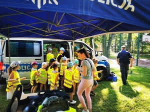 dzieci w odblaskowych kamizelkach odwiedzają stoisko informacyjne krośnieńskich policjantów oraz zwiedzają radiowóz