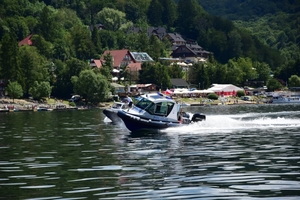Policyjna łódka, pływająca na Jeziorze Solińskim. w tle woda i zabudowania