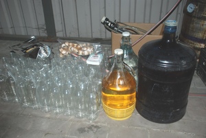 Zdjęcie kolorowe przedstawia rzeczy zajęte przez policję do produkcji nielegalnego alkoholu oraz wyrobów tytoniowych.