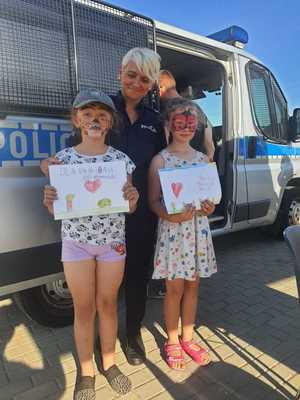 na zdjęciu policjantka z dziećmi stojąca przy policyjnym radiowozie