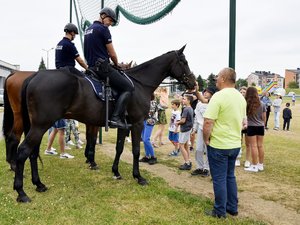na zdjęciu dwaj policjanci na koniach służbowych oraz kilkanaście osób w pobliżu
