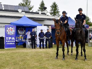 na zdjęciu dwaj policjanci na koniach w tle policyjny namiot z banerami oraz stojący w pobliżu umundurowani funkcjonariusze