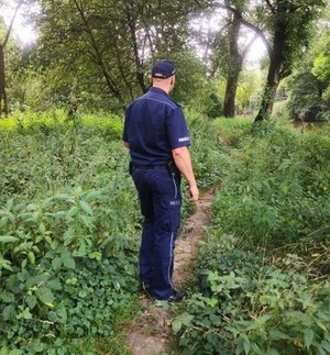 umundurowany policjant w czasie patrolu terenu nad rzeką