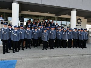 przed wejściem do budynku komendy policji stojący policjanci oraz zaproszeni goście - pamiątkowe zdjęcie grupowe