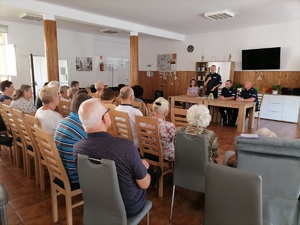 Seniorzy siedzą zwróceni twarzą w stronę środka sali, skąd przemawia do nich Komendant Powiatowy Policji w Łańcucie insp. Marek Mendoń.