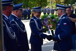 Po lewej policjantka składa gratulacje Komendantowi Wojewódzkiemu Policji w Rzeszowie, który trzyma szablę generalską (po prawej). Obok po lewej zastępcy komendanta.
