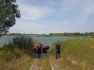 na fotografii policjanci nad wodą, w tle strażacka motorówka na wodzie