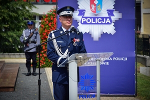 Komendant Główny Policji w centrum kadru przy mikrofonie, w tle banner z policyjną gwiazdą.