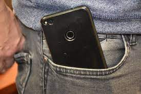 Zdjęcie kolorowe przedstawia mężczyznę ubranego w spodnie typu jeans i koszulkę kolorze czarnym z prawej przedniej kieszeni spodni widoczny jest telefon komórkowy w kolorze niebieskim