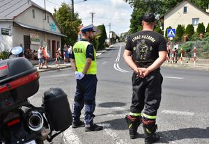 Policjant i strażak podczas zabezpieczenia przejazdu kolarzy