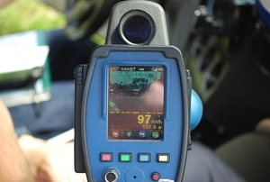 Na zdjęciu laserowy miernik do pomiaru prędkości trzymany przez policjanta.