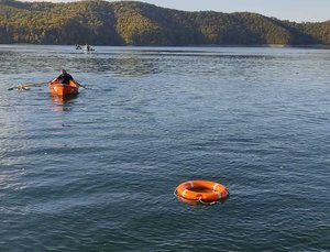 Jezioro, po którym pływa łódka z ratownikami, na pierwszym planie koło ratunkowe. Zdjęcie poglądowe
