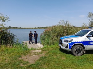 Zdjęcie kolorowe wykonane w porze dziennej przedstawia policjantów z Komisariatu Policji w Medyce którzy kontrolują  tz. „dzikie kąpieliska”