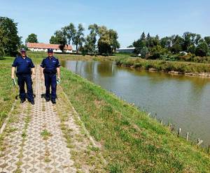 Zdjęcie kolorowe wykonane w porze dziennej przedstawia policjantów z Komisariatu Policji w Medyce którzy kontrolują  tz. „dzikie kąpieliska”