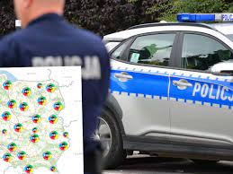 Zdjęcie kolorowe przedstawia policjanta stojącego koło radiowozu oznakowanego a w lewym rogu umieszczony jest plakat Krajowej Mapy Zagrożeń Bezpieczeństwa
