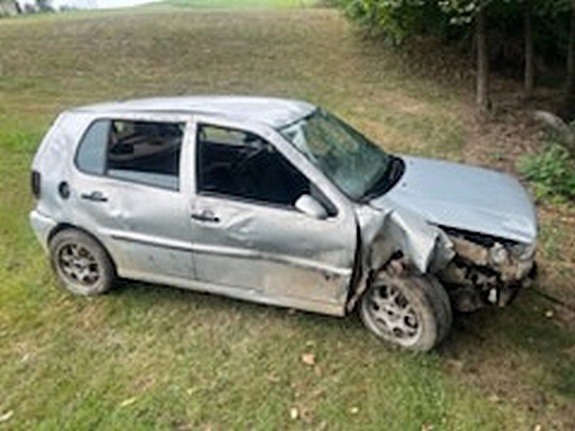 uszkodzony bok oraz przednia część srebrnego volkswagena. Samochód ustawiony na trawie nieopodal koryta rzeki
