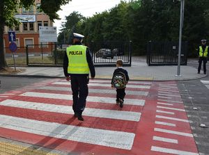 Policjant przeprowadza chłopca przez przejście dla pieszych