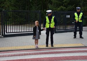 Policjantka przeprowadza małą dziewczynkę przez przejście dla pieszych