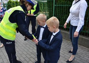 Policjantka zakłada odblaski na ręce chłopcom