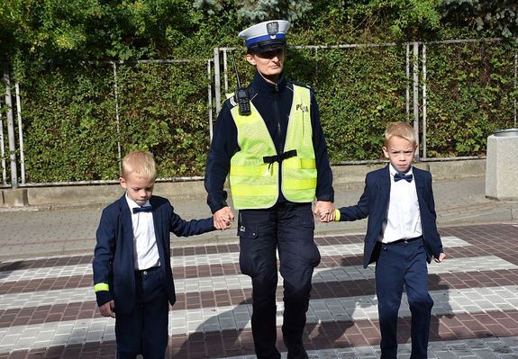 Policjantka przeprowadza przez przejście dla pieszych chłopców
