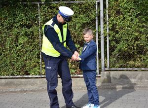 Policjant zakłada chłopcu opaskę odblaskową