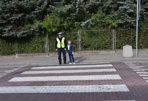 Policjant przeprowadza chłopca przez przejście dla pieszych