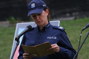 policjantka w umundurowaniu służbowym odczytuje fragment trzymanej w ręku lektury