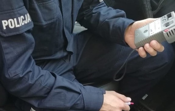 Na zdjęciu policjant, który trzyma urządzenie do badania stanu trzeźwości.