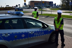 Policyjny radiowóz przy którym stoi dwoje policjantów ruchu drogowego