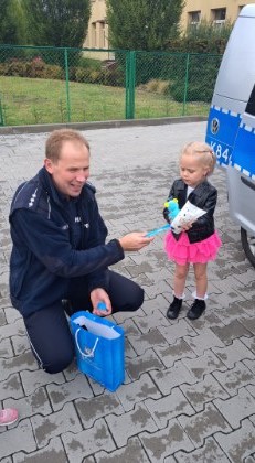 Policjant daje dziewczynce maskotkę