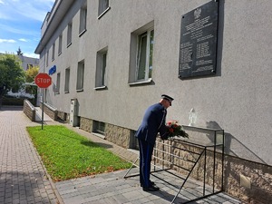 na zdjęciu Komendant Powiatowy Policji w Mielcu składa kwiaty przed tablicą na budynku KPP Mielec