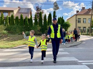 Policjant przeprowadza dzieci przez przejście dla pieszych