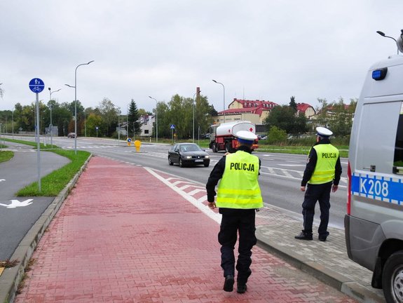 policjanci w umundurowaniu i żółtych kamizelka stojący na tle ruchliwej drogi