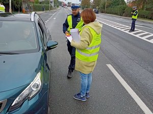 na zdjęciu umundurowany policjant oraz członek MKRPA w Jaśle w żółtych kamizelkach stojący przy zatrzymanym do kontroli samochodzie