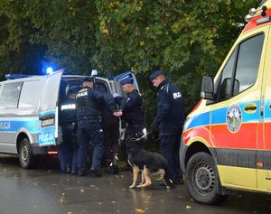 Ćwiczenie PERUN 2022. na zdjęciu radiowóz, przy nim policjanci i pies służbowy,  oraz karetka pogotowia