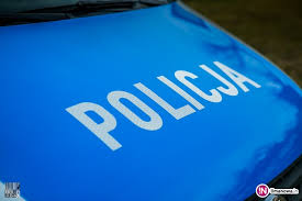 Zdjęcie kolorowe przedstawia maskę silnika radiowozu policyjnego w kolorze niebieskim na której widnieje napis „POLICJA” w białym kolorze