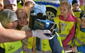 Policjant pokazuje dzieciom urządzenie do pomiaru prędkości