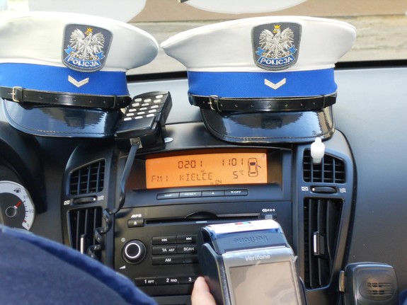 Dwie czapki policjantów ruchu drogowego leżące na podszybiu radiowozu
