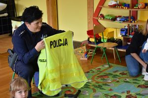 Policjantka pokazuje dzieciom elementy policyjnego umundurowania.