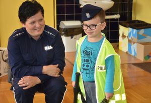 Policjanta z chłopcem ubranym w kamizelkę oraz policyjna czapkę