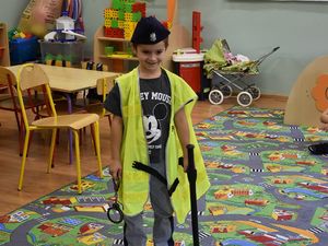 Chłopczyk ubrany w kamizelkę oraz policyjną czapkę