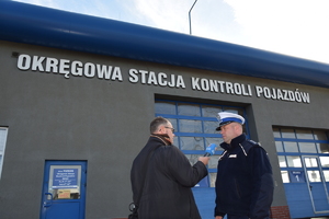 Policjant udziela wywiadu dziennikarzowi przed budynkiem Okręgowej Stacji Kontroli Pojazdów